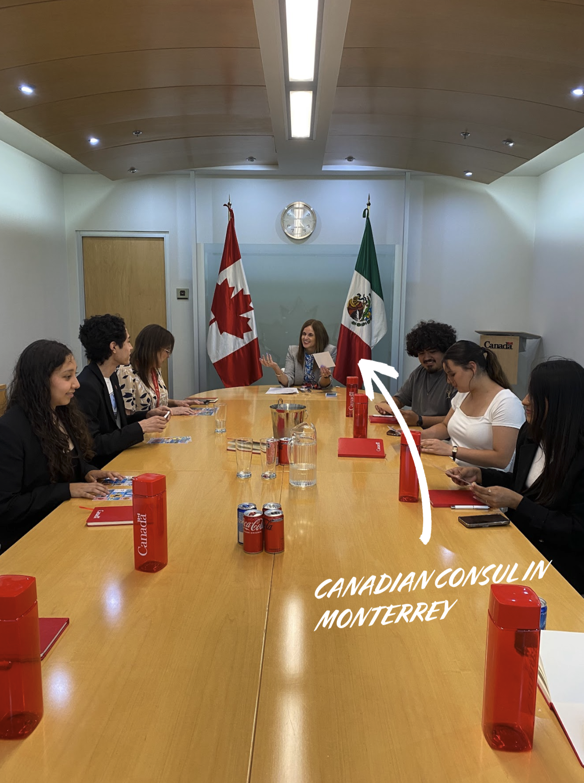 The AECAN team presenting Lotería Canadiense to the Canadian Consul in Monterrey, Canadian and Mexican flags behind the table