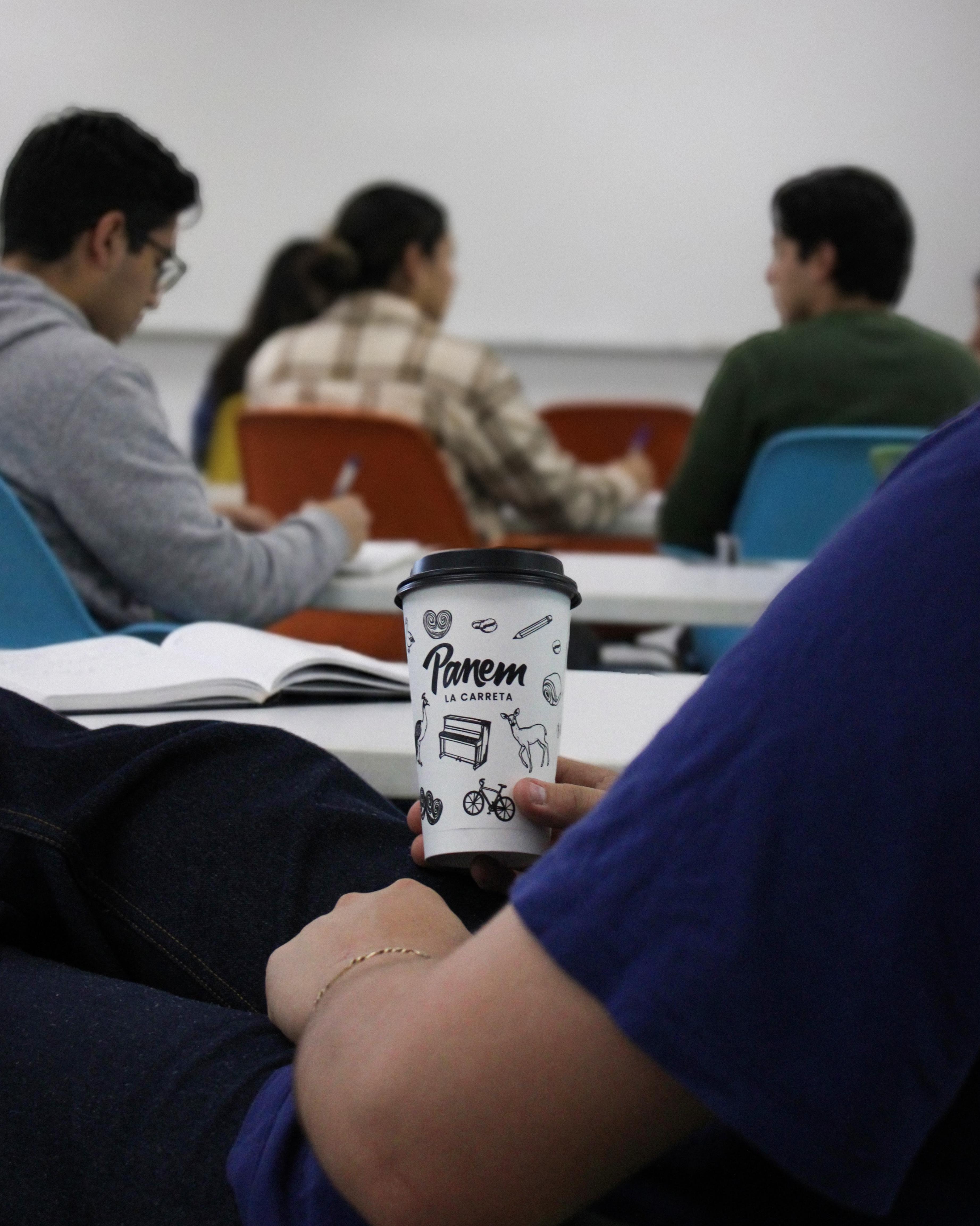 Student holding a Panem La Carreta cup in a campus classroom