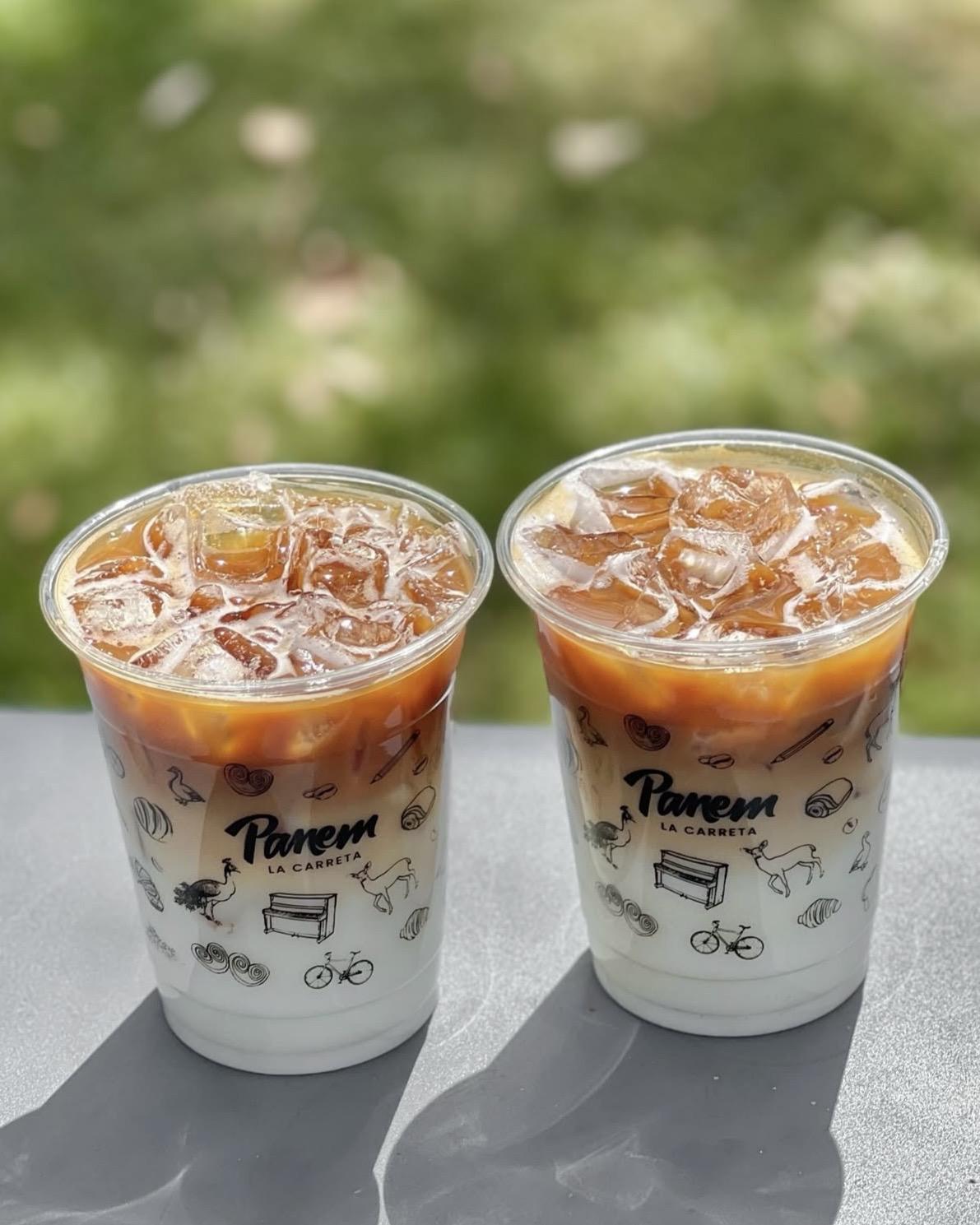 Two iced Panem coffees on a ledge against greenery